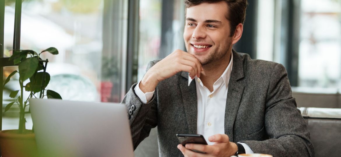 Smiling business man sitting by the table in cafe